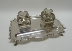 A SILVER DESK-STAND having a scrolling rim on four pad feet with pair of fitted inkwells, Birmingham
