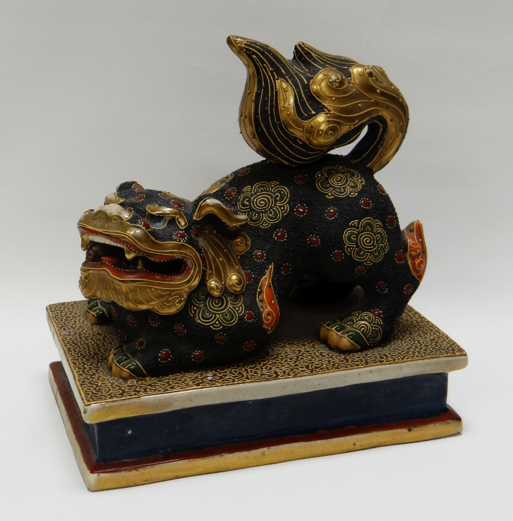 A JAPANESE POTTERY LION DOG decorated in the Satsuma style on a rectangular plinth base, 19cms long