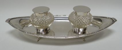 A SILVER INKSTAND OF MARQUISE DISH FORM with decorative border on four scroll feet and with pair