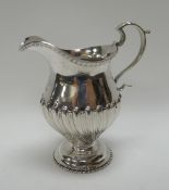 A SILVER CREAM JUG raised on a circular base and with relief swirl decoration to the body, 4.4ozs