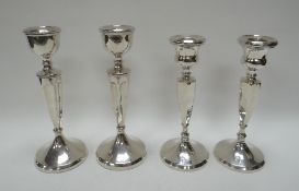 A NEAR-SET OF FOUR SILVER CANDLE HOLDERS on circular bases with fluted stems, 21ozs gross