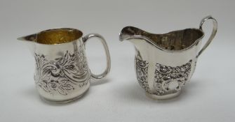 TWO SILVER CREAM JUGS of differing forms and with repoussé decoration to the bodies, 4.6ozs