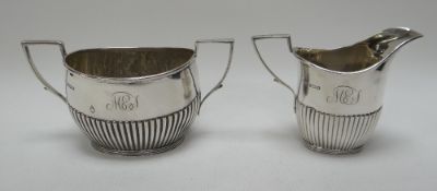 A SILVER CREAM JUG & MATCHING TWIN-HANDLED SUGAR BASIN with angular handles and fluted decoration