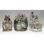 THREE NINETEENTH CENTURY STAFFORDSHIRE MODELS comprising a seated courting couple with dog beneath a