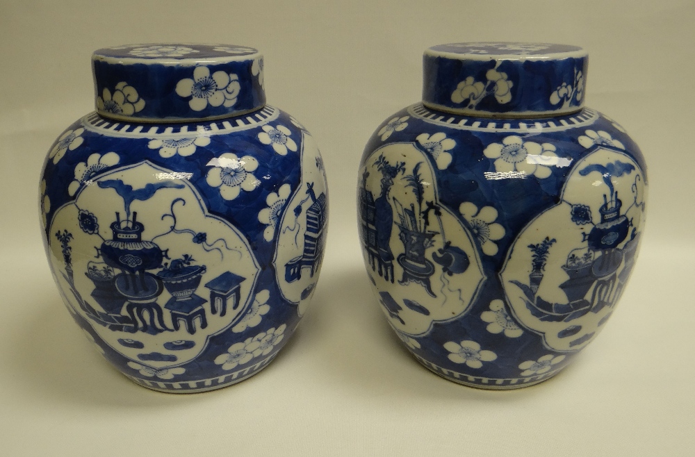 A PAIR OF CHINESE BLUE & WHITE JARS & COVERS each with four panels featuring items of domesticity