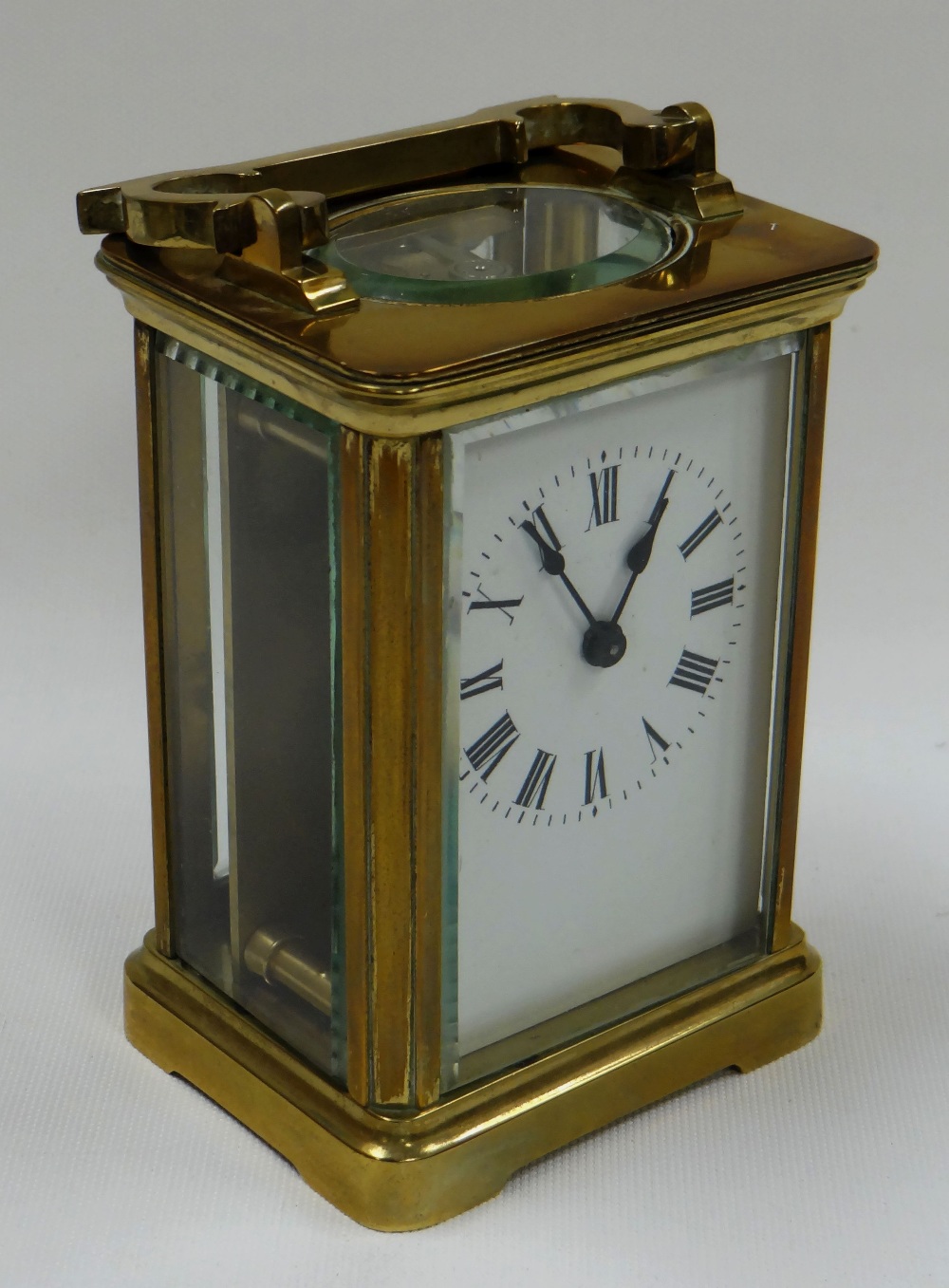 A BEVELLED GLASS CARRIAGE CLOCK bearing Roman numerals to the rectangular white dial (key with