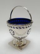 A SILVER SWING HANDLE SUGAR BASIN having a Bristol-blue glass liner, raised on a square base and