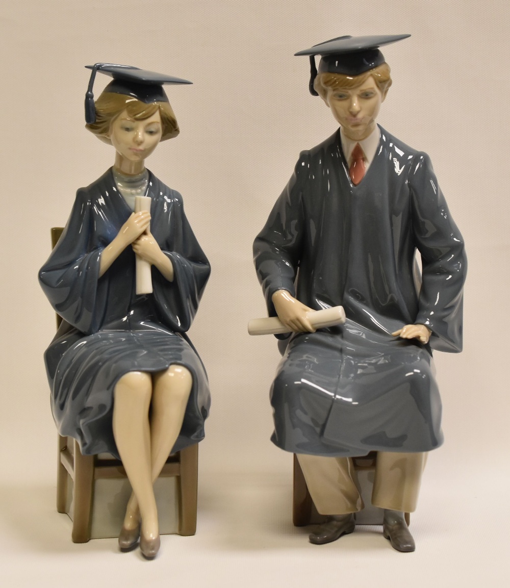 PAIR OF LLADRO FIGURES OF SEATED GRADUATING STUDENTS, one being male, the other female, 25 and 27cms