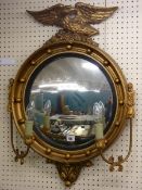 A CONVEX WALL MIRROR, gilt framed with ball decorated frame, eagle atop and with a pair of side