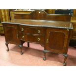 A MAHOGANY BOW FRONT SIDEBOARD with arched railback over a carved edge top, twin central bowed