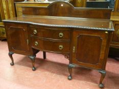 A MAHOGANY BOW FRONT SIDEBOARD with arched railback over a carved edge top, twin central bowed