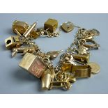 A NINE CARAT GOLD CHARM BRACELET with padlock clasp and over twenty charms including a one arm