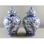 A LARGE PAIR OF JAPANESE JARS WITH COVERS, early 20th Century blue and white decorated with opposing