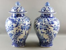 A LARGE PAIR OF JAPANESE JARS WITH COVERS, early 20th Century blue and white decorated with opposing