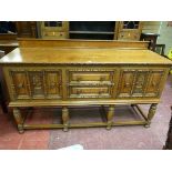 A JACOBEAN STYLE OAK RAILBACK SIDEBOARD, the moulded edge top over twin central drawers and flanking