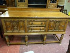 A JACOBEAN STYLE OAK RAILBACK SIDEBOARD, the moulded edge top over twin central drawers and flanking