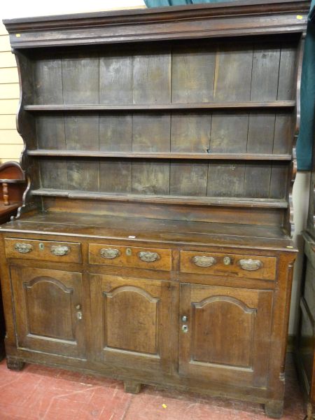 A LATE 18th/EARLY 19th CENTURY OAK DRESSER having a three shelf rack with shaped sides over a base