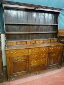 AN EARLY 19th CENTURY ALL OAK DRESSER having a three shelf rack with shaped ends and six spice