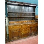 AN EARLY 19th CENTURY ALL OAK DRESSER having a three shelf rack with shaped ends and six spice