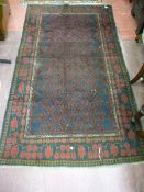 AN AFGHAN BELOUCHI TRIBAL RUG, deep red ground, wide bordered, 186 x 106 cms approximately