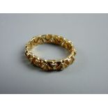 A FIFTEEN CARAT GOLD WEDDING BAND, scrolled and pierced and encrusted right round with tiny