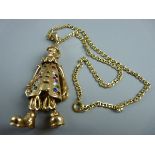 A NINE CARAT GOLD CLOWN PENDANT, 7 cms long, having jointed arms and feet and with precious stone