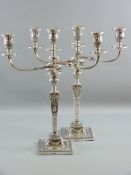 A PAIR OF SILVER CANDELABRA, square based with square tapered columns and decorated all over with