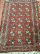 AN EASTERN WOOLLEN BOKHARA CARPET, hand knotted with central repeating pattern and wide multi-