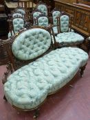 A NINE PIECE CARVED WALNUT SALON SUITE comprising an open ended couch, lady's and gent's armchairs