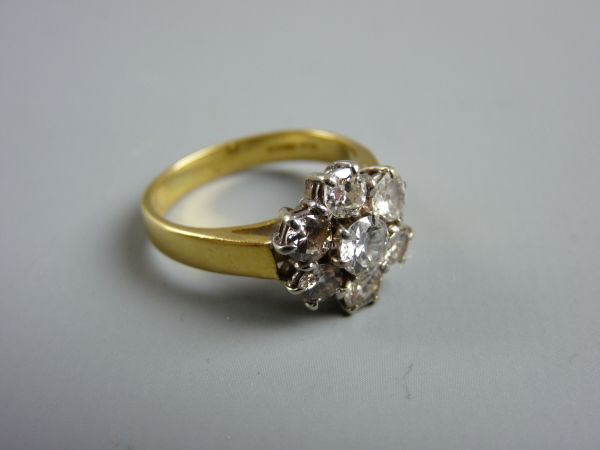 AN EIGHTEEN CARAT GOLD SEVEN STONE DIAMOND CLUSTER RING, 5.2 grms, the centre stone of visual