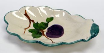 A LLANELLY POTTERY DISH of acorn-leaf shape, painted with a plum on a branch with leaves,