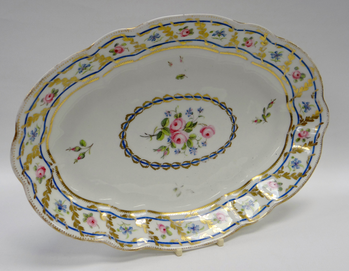 A SWANSEA PORCELAIN OVAL DISH of fluted form, the interior painted with three roses within a blue