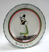A LLANELLY POTTERY PLATE ‘THE LAND OF THE LEEK’ of circular form with green and red trim, painted
