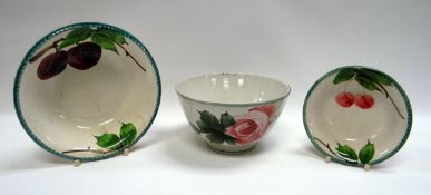 THREE LLANELLY POTTERY BOWLS comprising a shallow bowl painted with plums, 16cms diam a small bowl