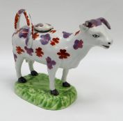 A SWANSEA POTTERY COW CREAMER standing on a grassy base, with looped tail as handle and decorated