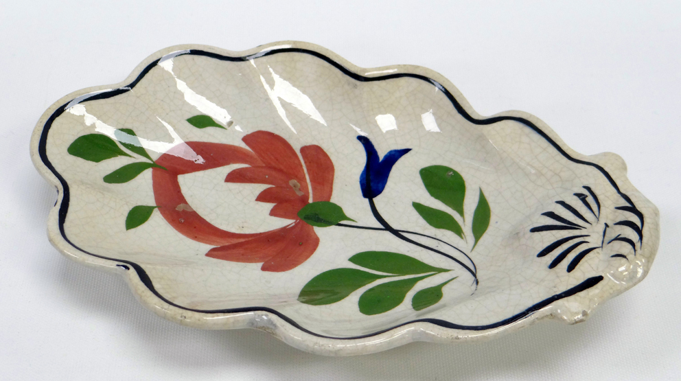A LLANELLY POTTERY DISH of acorn-leaf shape, painted with a stylised flowers with leaves,