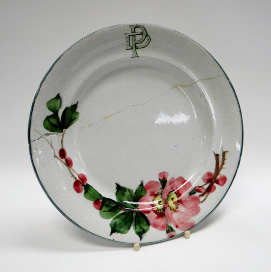 A LLANELLY POTTERY MONOGRAMMED PLATE painted with wild-roses, the border with stylised monogram ‘DP’