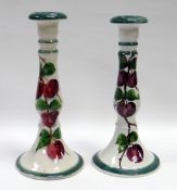 A PAIR OF LLANELLY CANDLESTICKS of circular form, painted with plums on a vine, by Shufflebotham,