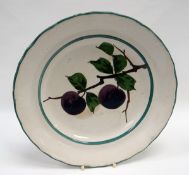 A LLANELLY POTTERY PLATE having a wavy rim, the interior painted with two plums on branches by