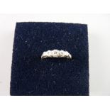 AN EIGHTEEN CARAT GOLD DIAMOND RING with a band of five small graduated diamonds and with tiny