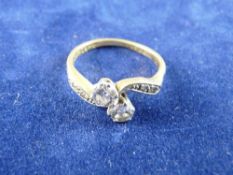 AN EIGHTEEN CARAT GOLD TWO STONE DIAMOND RING with tiny diamond shoulders, visual estimate of each