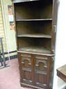 A REPRODUCTION OAK TWO PIECE STANDING CORNER CUPBOARD, the inverted cornice over a twin shelf open