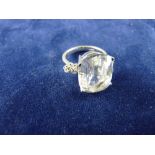 A NINE CARAT WHITE GOLD DRESS RING with large oval cz, flanked on each side by two tiny diamonds,