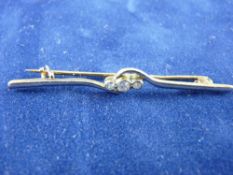 A FIFTEEN CARAT GOLD DIAMOND BAR BROOCH with three small round cut diamonds, 4 grms