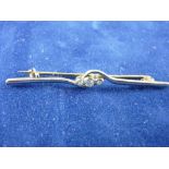 A FIFTEEN CARAT GOLD DIAMOND BAR BROOCH with three small round cut diamonds, 4 grms