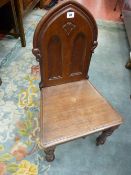 A VICTORIAN MAHOGANY HALL CHAIR, arched ecclesiastical style back with solid seat on turned front