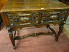 A REPRODUCTION OAK LOWBOY with twin Flemish style carved drawers having iron ring pull handles,