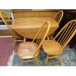 AN ERCOL LIGHT ELM DROP LEAF DINING TABLE AND FOUR CHAIRS having raised hoop with stick backs