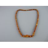 A GRADUATED AMBER BEAD NECKLACE with screw-in clasp, fifty four in total, 2 cms the largest, 61