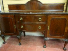 A MAHOGANY BOW FRONT SIDEBOARD with arched railback over a carved edge top, twin central bowed